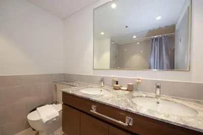 a bathroom with two sinks and a toilet and a mirror at Downtown Luxury - Stunning 2BHK with Sea view in Forte towers, Downtown in Dubai