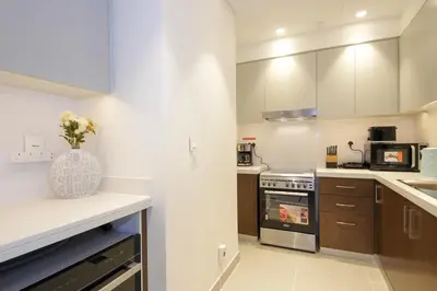 a kitchen with white cabinets and a vase of flowers at Downtown Luxury - Stunning 2BHK with Sea view in Forte towers, Downtown in Dubai