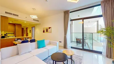 a living room with a white couch and a table at Locations I Avanos Residence I Premium Modern 1BR I Cosy & Comfortable I Near Parks, Shops & Cafés in JVC in Dubai