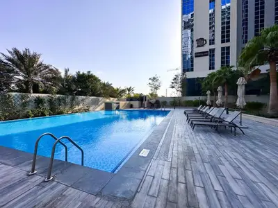 a swimming pool with benches and chairs next to a building at Luxurious 2BR in Vezul Residence, Business Bay - 13AB01 in Dubai
