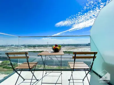 a table and chairs on a balcony with a view of an airport at Amazing Studio with Balcony & View Riviera Meydan in Dubai