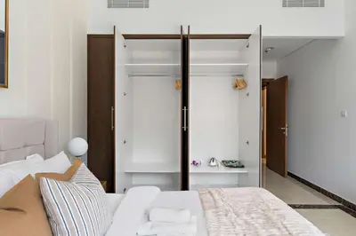 a bedroom with a white bed and a closet at Silkhaus Modern 2BDR in Pantheon Boulevard at JVC in Dubai