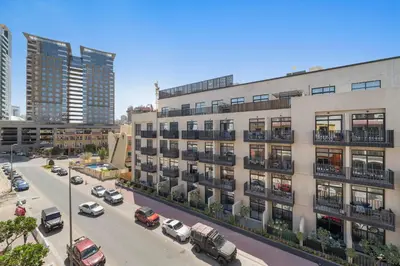an apartment building with cars parked in a parking lot at Silkhaus Modern 2BDR in Pantheon Boulevard at JVC in Dubai