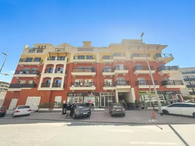 a large building with cars parked in a parking lot at Silkhaus Modern 2BDR in Pantheon Boulevard at JVC in Dubai