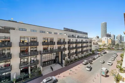 an apartment building with cars parked in a parking lot at Silkhaus Modern 2BDR in Pantheon Boulevard at JVC in Dubai
