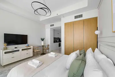 a white bedroom with a large white bed and a television at Silkhaus New Modern Studio In New Tower at Business Bay in Dubai