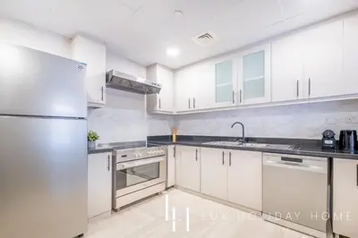 a kitchen with white cabinets and a stainless steel refrigerator at LUX The Luxurious Central JBR Suite 2 in Dubai