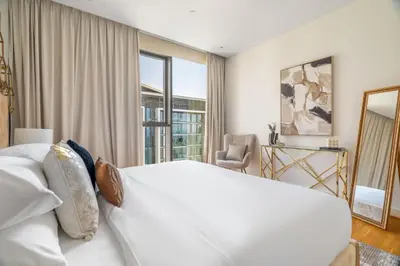 a white bedroom with a large bed and a chair at GuestReady - Magnificent stay in Bluewaters Island in Dubai