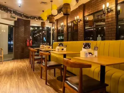 a restaurant with yellow walls and wooden tables and chairs at Cosmos Living Sleek and Stylish GCV2 in Dubai