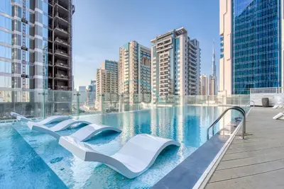 a swimming pool with escalators in a city with tall buildings at Stunning 3BR Apartment in Bayz Tower, Business Bay by Deluxe Holiday Homes in Dubai