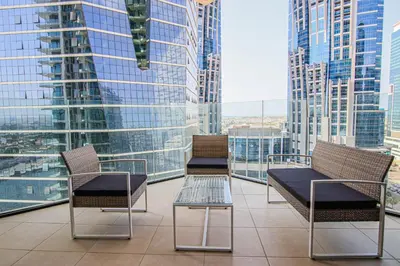 three chairs and a table on a balcony with skyscrapers at 1BR Apt Residence Along Business Bay Canal in Dubai