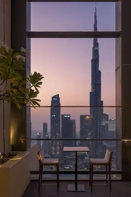 a room with a table and two chairs and a view of a city at Glow Sky Suite Trendy 1BR- Dubai Mall Access by Maxx Value Homes in Dubai