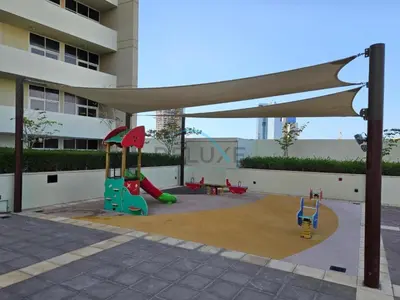 a playground with two play equipment in front of a building at Elegant 2BR in Tower 108 Jumeirah Village Circle by Deluxe Holiday Homes in Dubai