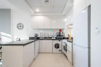a kitchen with white cabinets and a washer and dryer at Elegant 2BR in Tower 108 Jumeirah Village Circle by Deluxe Holiday Homes in Dubai