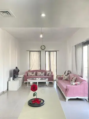 a living room with pink couches and a red rose on a table at Lovely calm 3BR Apt Easy Accessibility to central Dubai with huge balcony and pool view Town Square in Dubai