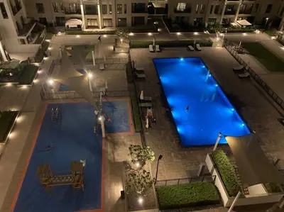 an overhead view of a large swimming pool at night at Lovely calm 3BR Apt Easy Accessibility to central Dubai with huge balcony and pool view Town Square in Dubai