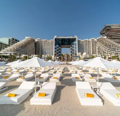 a beach with white lounge chairs and umbrellas at FIVE Palm Residence - Elegant Home in Dubai