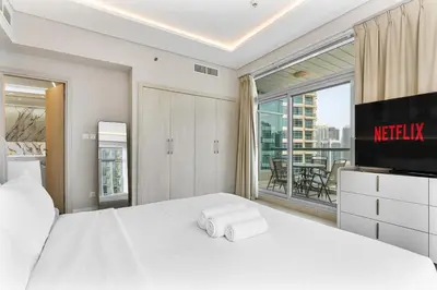 a bedroom with a white bed with a television and a balcony at Gorgeous 2BR APT in Dubai Marina with Canal View in Dubai