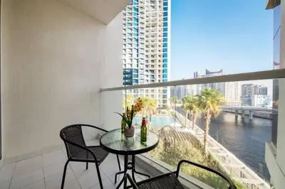 a balcony with a table and chairs and a view of the water at Luxury Smart Studio with Canal View Business Bay - Damac Maison Prive in Dubai