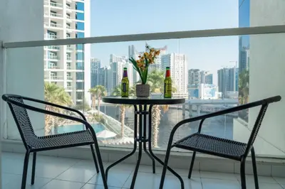 two chairs and a table with two bottles of wine at Luxury Smart Studio with Canal View Business Bay - Damac Maison Prive in Dubai
