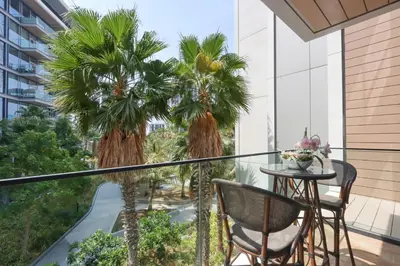 a balcony with palm trees and a table and chairs at Livbnb - Luxury 3B with Maid's Room, Partial Sea View in Dubai