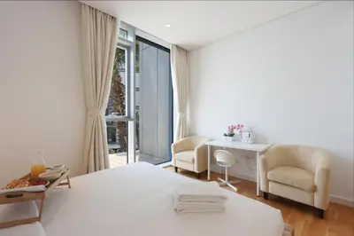 a white bedroom with a bed and a desk and chairs at Livbnb - Luxury 3B with Maid's Room, Partial Sea View in Dubai