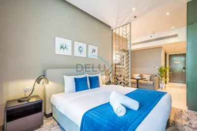 a bedroom with a large bed with blue pillows at Luxury Studio Apartment in Prive By Damac B, Business Bay by Deluxe Holiday Homes in Dubai