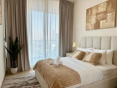 a bedroom with a large bed with a large window at Modern 1br In Jvc Pool, Balcony & Free Parking in Dubai
