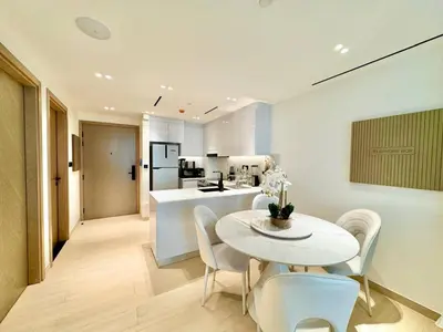 a kitchen and dining room with a white table and chairs at Modern 1br In Jvc Pool, Balcony & Free Parking in Dubai