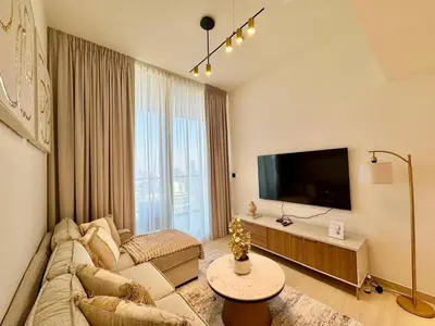 a living room with a couch and a flat screen tv at Modern 1br In Jvc Pool, Balcony & Free Parking in Dubai