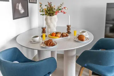 a table with plates of food on it with blue chairs at Stylish 1BR with Iconic Burj and Fountain Views, Free Luxury Airport Pick Up Service in Dubai