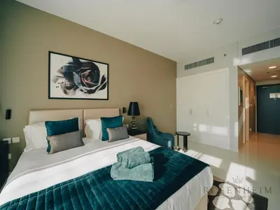 a bedroom with a large bed with a blue blanket at Modern Studio Escape - Pool, Gym & Relaxation in Dubai
