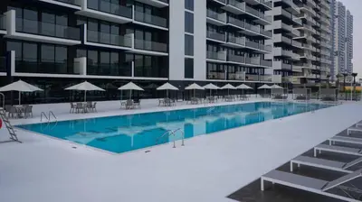 a swimming pool with tables and umbrellas next to a building at Cozy & Stylish 1br Apt Jvc Pool & Parking in Dubai