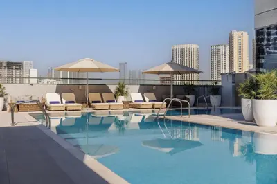 a swimming pool with chairs and umbrellas on a building at Holiday Inn Dubai Jumeirah Village Circle by IHG in Dubai