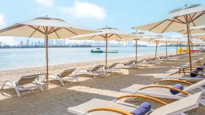 a row of chairs and umbrellas on a beach at Holiday Inn Dubai Jumeirah Village Circle by IHG in Dubai