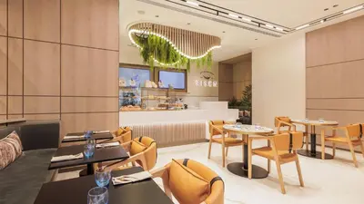 a restaurant with tables and chairs and a counter at Holiday Inn Dubai Jumeirah Village Circle by IHG in Dubai
