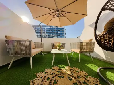a patio with chairs and a table and an umbrella at Naseem Elegant Studio Escape in Al Merkadh in Dubai
