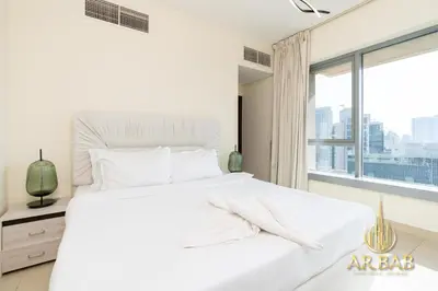 a white bedroom with a large white bed and a window at 29 Burj Boulevard - Premium 1BR - City Skyline view - Near Burj Khalifa - Downtown Dubai in Dubai