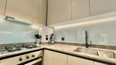 a kitchen with white cabinets and a stove and a sink at 2BR with Extra-Large Balcony Canal & Burj Views by Vibel in Dubai