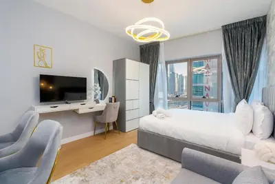 a bedroom with a bed and a desk and a tv at White Sage Stunning New Studio in Marina in Dubai