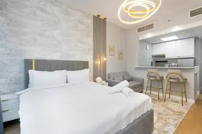 a bedroom with a large white bed and a kitchen at White Sage Stunning New Studio in Marina in Dubai