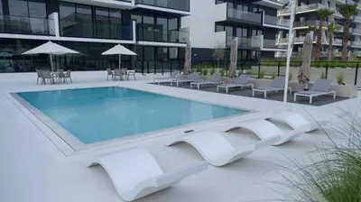 a swimming pool in front of a building at Stylish 1br Apt In Jvc Pool Access & Parking in Dubai