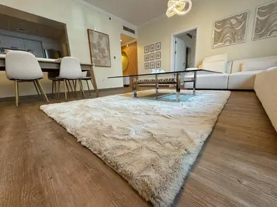 a living room with a glass table and a rug at DreamShoma- Deluxe 1BR With Lake View in Dubai