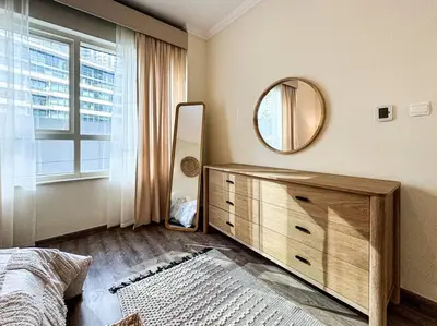 a bedroom with a dresser and a mirror and a window at DreamShoma- Deluxe 1BR With Lake View in Dubai