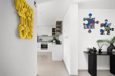 a hallway with a white kitchen with a lego wall at Arthouse Views - Burj Khalifa view & Dubai Mall access in Dubai
