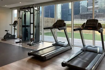 a gym with three tread machines and a large window at Waves - Canal-View Elegance 1BR Apt in Reva Residences in Dubai