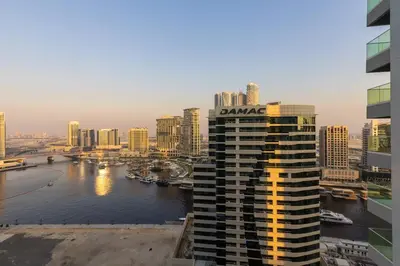 a building with a sign on top of it next to a river at Waves - Canal-View Elegance 1BR Apt in Reva Residences in Dubai