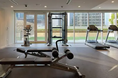 a gym with several tread machines in a room with windows at Waves - Canal-View Elegance 1BR Apt in Reva Residences in Dubai