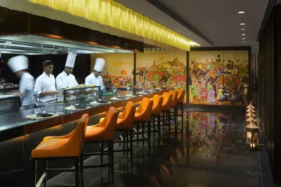 a restaurant with a line of chefs preparing food at Taj Dubai in Dubai