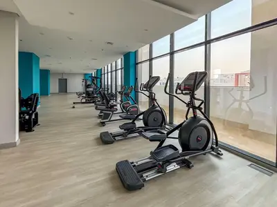 a row of exercise bikes in a gym with windows at Frank Porter - Azizi Riviera 28 in Dubai